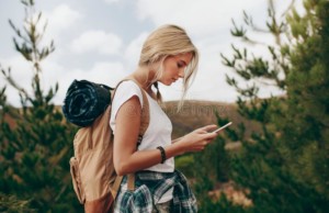 Les meilleures applications mobiles pour les voyageurs nomades – Sa 1684510435 vue de côté d un voyageur femme regardant son téléphone portable